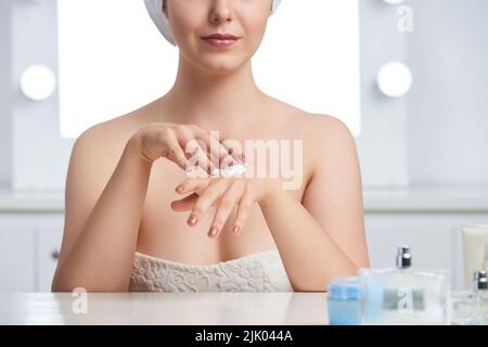 Nahaufnahme einer jungen Frau, die Feuchtigkeitscreme auf ihren Körper anwendet Stockfoto
