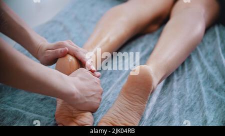 Massage - Massage Master massiert Frauen Beine und Füße mit Öl Stockfoto