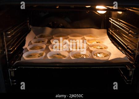 Papierkisten gefüllt mit Muffinteig Stockfoto