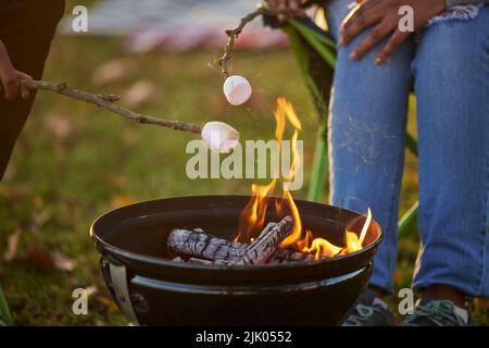 Es gibt niemanden, der lieber hier sein wird. Ein Paar, das während des Campens Marschmelzchen röstet. Stockfoto