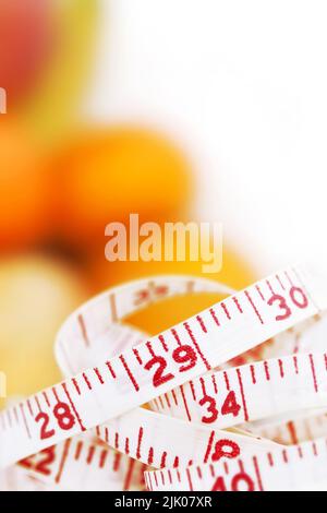 Weight Watcher - Maßband mit verschiedenen Früchten im Hintergrund Stockfoto