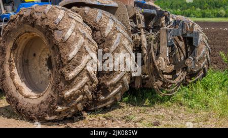 Schmutzige Doppelräder der Landwirtschaft Traktor auf Feldweg an sonnigen Sommertag Stockfoto