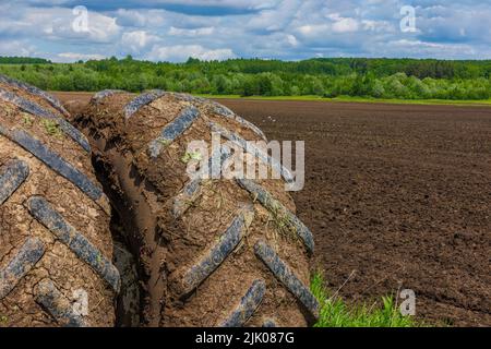 Schmutzige Doppelräder der Landwirtschaft Traktor an sonnigen Sommertag mit gepflügten Feld im Hintergrund Stockfoto