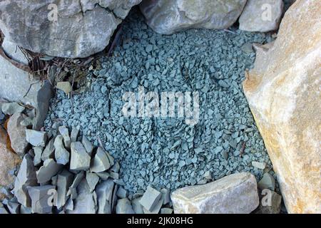 Ein Stein zerfiel am Fluss in kleine Stücke. Stockfoto