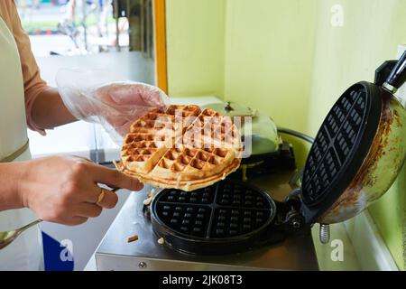 Frau, die frisch gebackene belgische Waffeln aus dem Waffeleisen nahm Stockfoto