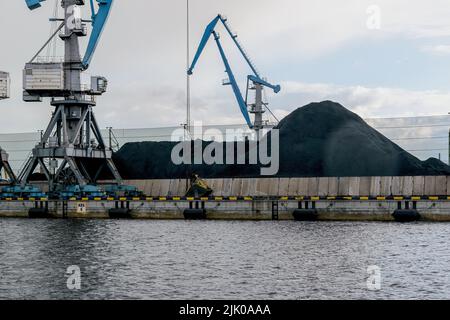 Frachtkrane im Hafen Kohle Terminal. Haufen Kohle auf dem Pier. Stockfoto