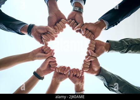 Wir können alles gemeinsam erreichen. Unten eine Aufnahme einer Gruppe von nicht erkennbaren Geschäftsleuten, die sich in einer Einheit zusammenschließen. Stockfoto