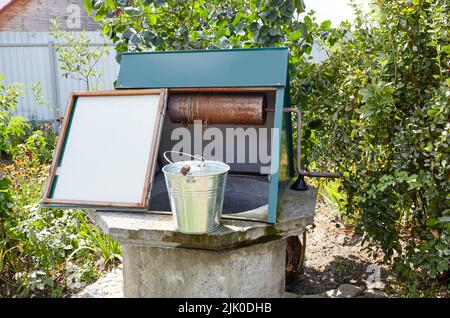 Alte Ziehbrunnen im europäischen Dorf. Retro Steinwasserbrunnen in ländlicher Umgebung Stockfoto