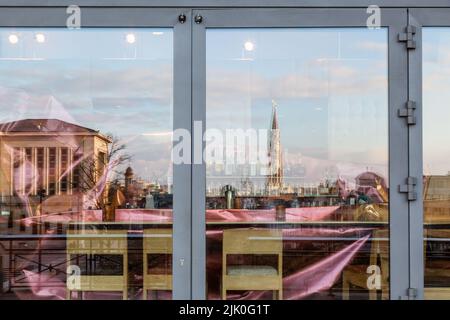 Stadtbild des Zentrums von Brüssel, mit dem Turm des Rathauses, spiegelt sich in den Fenstern eines Restaurants auf dem Mont des Arts Stockfoto