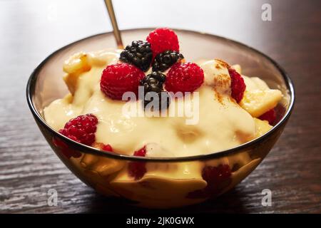 Frischer, leckerer Obstsalat mit Joghurt auf Holztisch Stockfoto