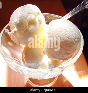 Köstliche Kugeln aus cremigem Eis in einer von Sonnenlicht beleuchteten Vase. Stockfoto