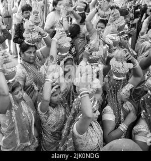 Delhi, Indien April 03 2022 - Frauen mit Kalash am Kopf während des Jagannath-Tempels Mangal Kalash Yatra tragen indische Hindu-Anhänger irdische Töpfe im Container Stockfoto