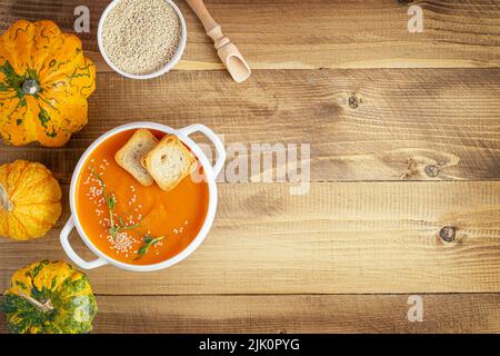 Kürbissuppe mit Croutons und Sesamsamen auf Holzhintergrund. Kopierbereich, Draufsicht Stockfoto