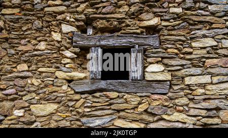 Kleines Holzfenster in traditioneller Wand aus Stein, Steinstruktur und Hintergrund. Madrid. Stockfoto