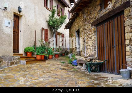 Kleine Ecke in einer Gasse einer Altstadt mit Blumentöpfen, Blumen und Schubkarre. Madrid. Stockfoto