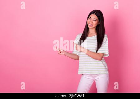 Portrait of adorable zufrieden thai Person zeigen Finger leeren Raum Förderung isoliert auf rosa Hintergrund Stockfoto