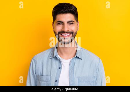 Nahaufnahme Foto von jungen zuversichtlich Kerl tragen Denim Shirt lächelnd Blick direkt isoliert auf hellgelben Hintergrund Stockfoto