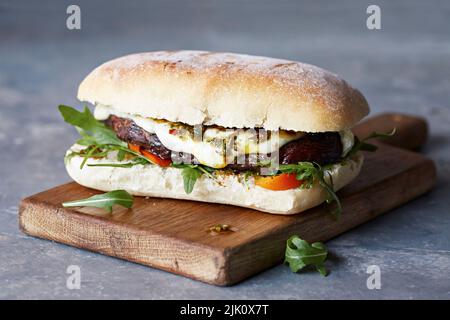 Steak-Sandwich mit geschmolzenem Käse und Rucola-Blättern Stockfoto