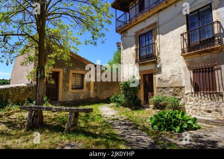 Fassade von alten Häusern mit kleinem Garten mit alter Holzbank. Sepulveda Spanien. Stockfoto