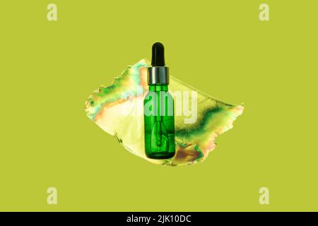 Flasche mit Tropf und Serum grüne Farbe. In einer Plastiktüte, die durch Photoelastizität in Regenbogenfarben gefärbt ist. Futuristisches Konzept. Stockfoto