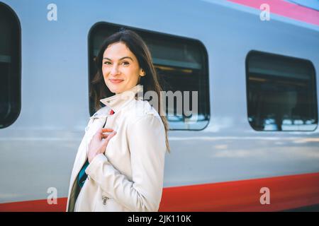 Porträt einer Geschäftsfrau, die mit Handgepäck in einem Bahnhof oder Flughafen zum Boarding Gate geht Stockfoto