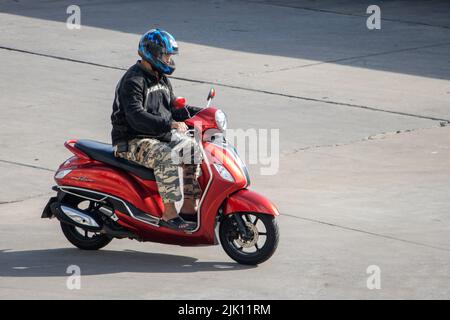 SAMUT PRAKAN, THAILAND, MAI 30 2022, Ein Mann mit Helm fährt ein Motorrad auf der sonnigen Straße Stockfoto