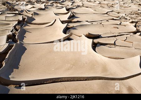 Abstraktes Muster aus trockenem, rissem Lehmschlamm im ausgetrockneten Flussbett, verursacht durch längere Trockenheit und heiße Temperaturen. Swakop River, Namibia, Afrika Stockfoto