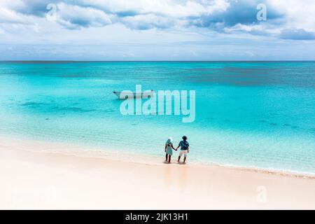 Mann und Frau halten sich an einem tropischen Strand und bewundern das kristallklare Meer, die Luftaufnahme, Antigua und Barbuda, Westindien, Karibik Stockfoto