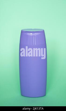 Violette Plastikflasche mit Körperpflege- und Schönheitsprodukten. Studio-Fotografie von Plastikflasche für Shampoo, Duschgel, Creme isoliert auf grün Stockfoto