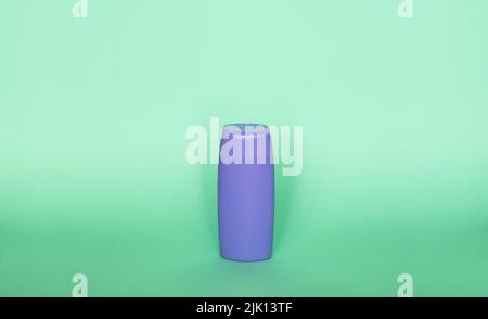 Violette Plastikflasche mit Körperpflege- und Schönheitsprodukten. Studio-Fotografie von Plastikflasche für Shampoo, Duschgel, Creme isoliert auf grün Stockfoto