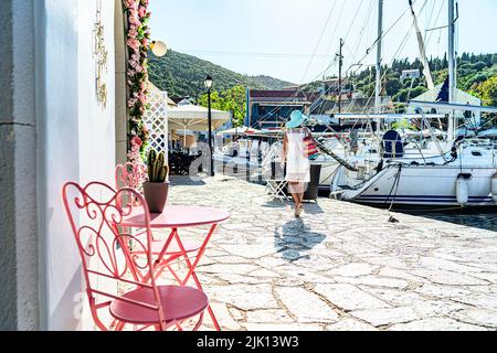 Frau, die Segelboote im kleinen Hafen des Küstendorfes Fiskardo, Kefalonia, Ionische Inseln, griechische Inseln, Griechenland, Europa Stockfoto