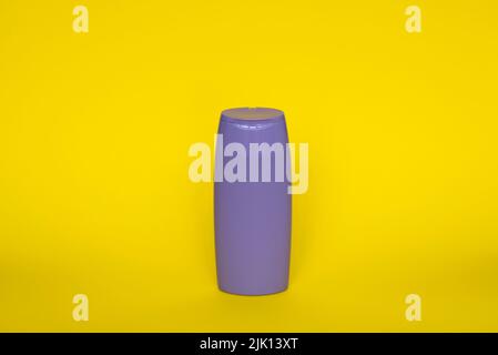 Violette Plastikflasche mit Körperpflege- und Schönheitsprodukten. Studio-Fotografie von Plastikflasche für Shampoo, Duschgel, Creme isoliert auf gelb Stockfoto