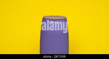 Violette Plastikflasche mit Körperpflege- und Schönheitsprodukten. Studio-Fotografie von Plastikflasche für Shampoo, Duschgel, Creme isoliert auf gelb Stockfoto