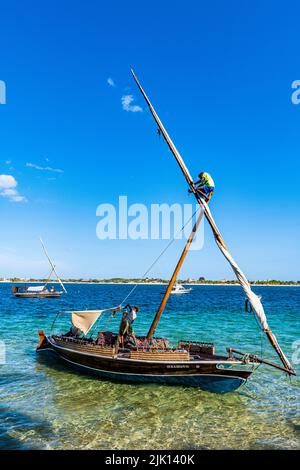 Junge klettert auf dem Mast einer traditionellen Dhow, Insel Lamu, Kenia Stockfoto