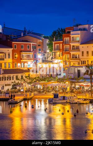 Blick auf Cafés, Restaurants und Boote im Hafen in der Abenddämmerung, Cales Fonts, Es Castell, Menorca, Balearen, Spanien, Mittelmeer, Europa Stockfoto