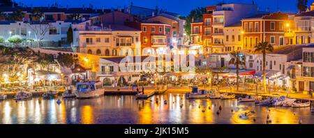 Blick auf Cafés, Restaurants und Boote im Hafen in der Abenddämmerung, Cales Fonts, Es Castell, Menorca, Balearen, Spanien, Mittelmeer, Europa Stockfoto