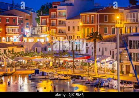 Blick auf Cafés, Restaurants und Boote im Hafen in der Abenddämmerung, Cales Fonts, Es Castell, Menorca, Balearen, Spanien, Mittelmeer, Europa Stockfoto