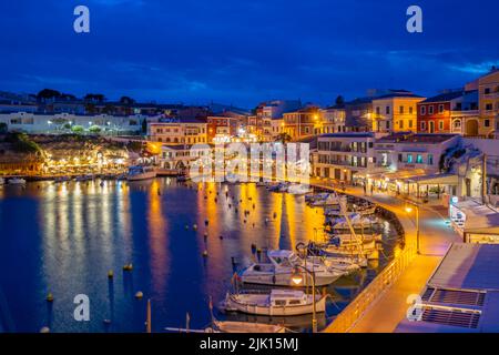 Blick auf Cafés, Restaurants und Boote im Hafen in der Abenddämmerung, Cales Fonts, Es Castell, Menorca, Balearen, Spanien, Mittelmeer, Europa Stockfoto