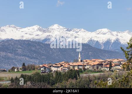 Panorama über das Dorf Sfruz mit schneebedeckten Berggipfeln vor blauem Himmel, Trentino, Italien Stockfoto