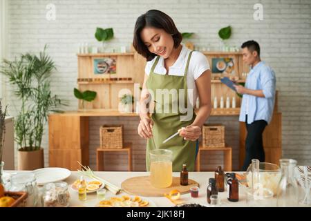 Hübsche vietnamesische Frau, die Seife macht, als ihr Mann sie online verkauft Stockfoto