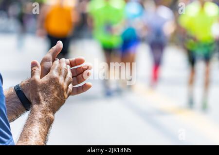 Beifall von einem nicht erkennbaren Mann bei einem Leichtathletik-Marathon, Sportkonzept. Stockfoto
