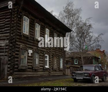 Altes Holzhaus in Tomsk, Westsibirien mit Auto, das draußen geparkt ist Stockfoto