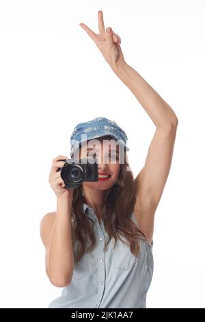 Attraktive lächelnde junge Frau, die Siegesgeste zeigt und Fotos macht Stockfoto