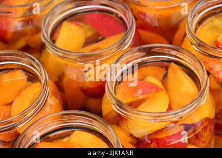 Hoch angesetzt, Nahaufnahme von Aprikosenscheiben mit Wasser und Zucker in Gläsern. Hausgemachte Fruchtkompott, fertig zum Verlecken und Sterilisieren. Vorbereitung Winter suppl Stockfoto