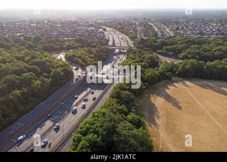 Kreisverkehr am Wasserwerk in Walthamstow. Ein großer Kreisverkehr mit der zweispurigen Straße A406, die in der Morgensonne durch den Wald führt Stockfoto