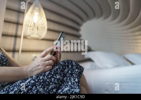 Frau, die nachts in ihrem Schlafzimmer auf das Mobiltelefon schaute. Spanien. Stockfoto
