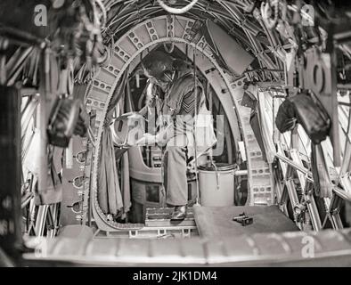 Ein Besatzungsmitglied an Bord eines Vickers Wellington der RAF-Staffel Nr. 75 (Neuseeland) platziert Nachtflackern im engen hinteren Rumpf. Der Wellington war ein britischer zweimotoriger, mittelgroßer Langstreckenbomber, der Mitte 1930s als Nachtbomber in den frühen Jahren des Zweiten Weltkriegs entwickelt wurde und bis zur Ablösung durch die größeren viermotorigen „Schweren“ wie den Avro Lancaster als einer der wichtigsten Bomber auftrat. Sie hat den Unterschied, dass sie der einzige britische Bomber war, der für die Dauer des Krieges produziert wurde. Stockfoto