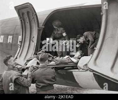 Luftbesatzung und WAAF-Pflegekräfte helfen dabei, einen Schlachtenopfer auf eine Bahre in eine Douglas Dakota Mark III der RAF-Staffel Nr. 233 zu laden. Die ersten „Kasevac“-Flüge der RAF nach Frankreich wurden am 13. Juni 1944 von Dakotas der No. 46 Group durchgeführt, und die Pflegekräfte der WAAF waren die ersten Frauen, die für diese Aufgaben beschäftigt waren.“ Stockfoto