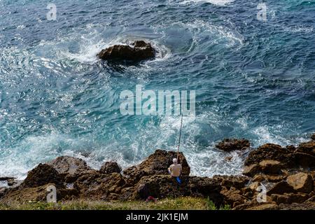 Der Mensch fischte auf den Felsklippen mit starken Wellen des Meeres. Santander Spanien. Stockfoto