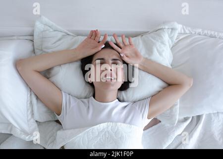 Draufsicht, depressive Frau, die im Bett liegt und vor Traurigkeit weint und schreit. Stockfoto